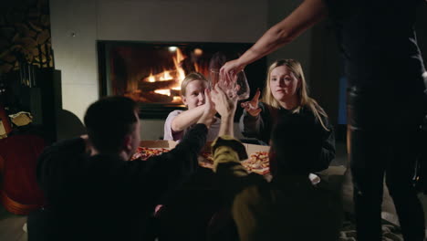 friends enjoying pizza and drinks by the fireplace