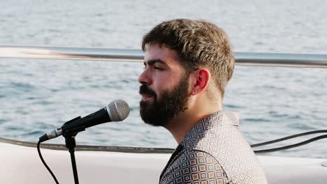 man singing through a microphone on a catamaran sail boat