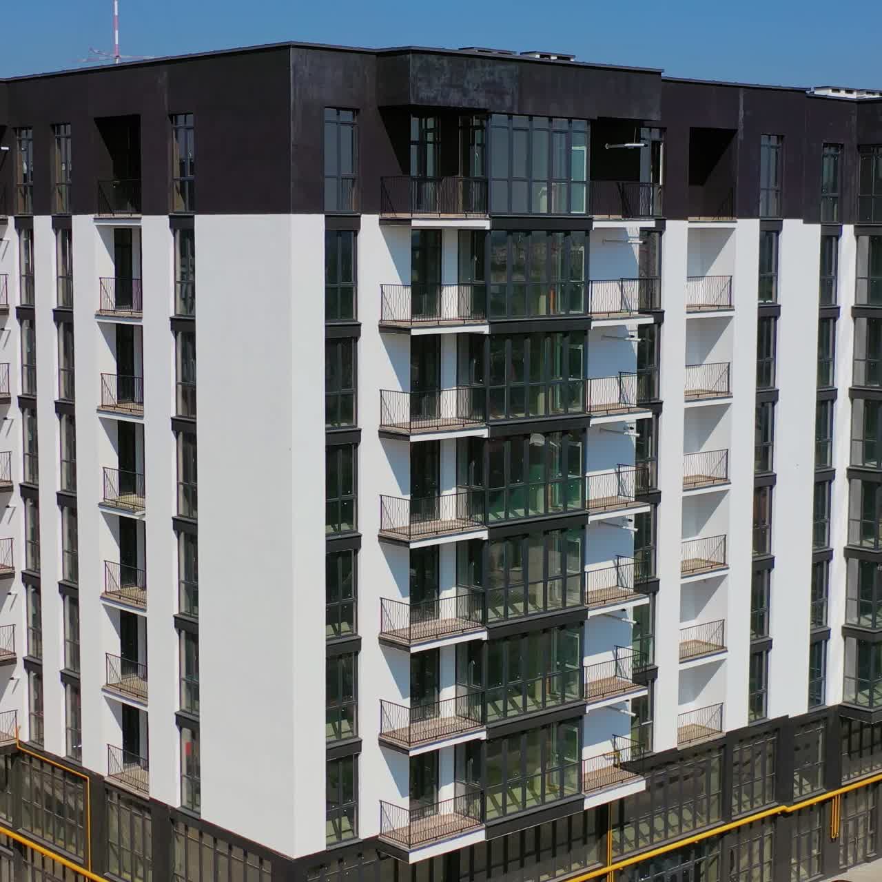 New architecture in the city. Luxury design of apartment building in a sunny day. Black and white high-rise apartment with balconies.