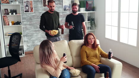 joven dando patatas fritas a sus amigos mientras ve un programa de televisión