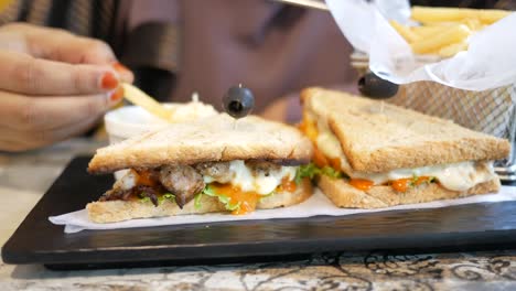 woman eating a grilled sandwich with fries