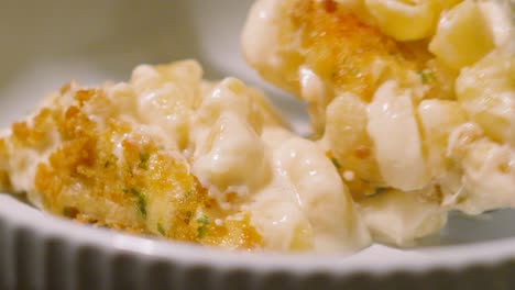 macaroni cheese meal rolling onto plate from serving spoon with crispy bread crumb coating. pasta based main dinner dish