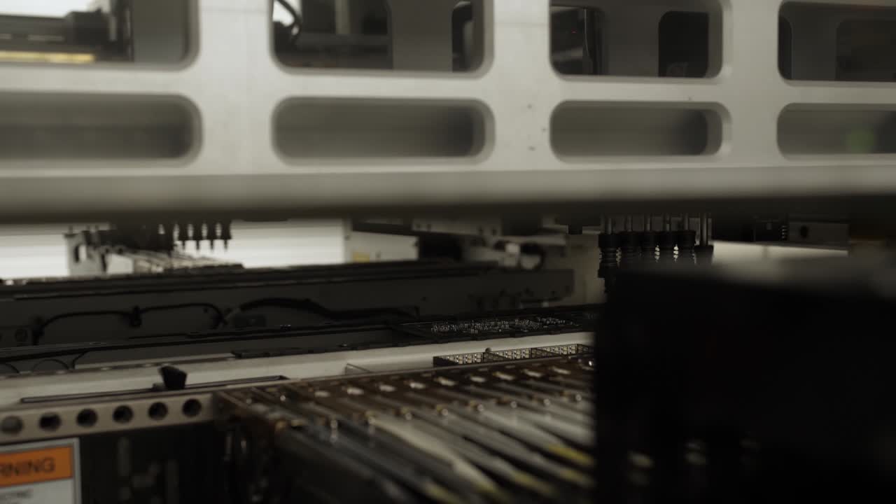 Automatic SMD pick and place machine during work - assembly of computer printed circuit board at factory