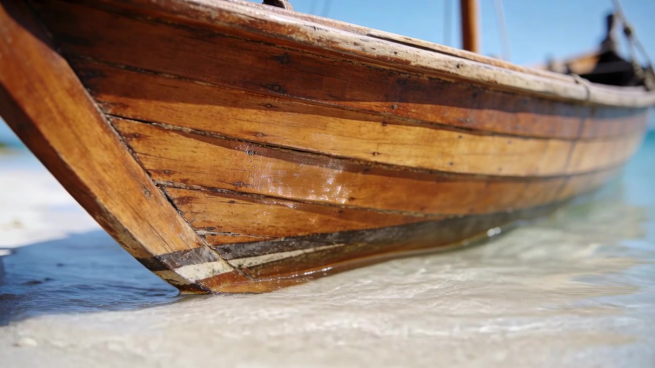 Prua di legno verniciato che ondeggia mentre le onde si infrangono, lambendo lo scafo sulla sabbia bassa e creando riflessi.