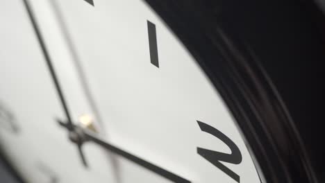 white clock face close up in time lapse on dark grey wall