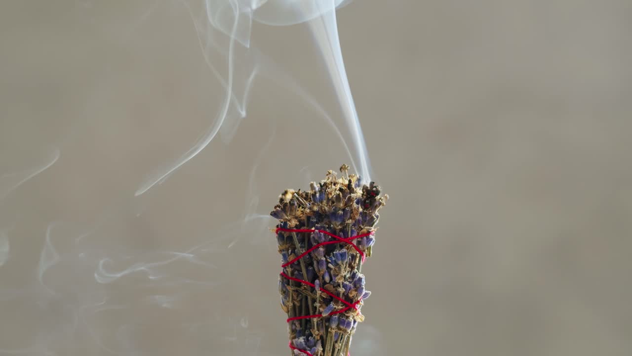 Person holding Palo Santo wood stick in hand, aromatic Palo Santo burning on black background, smoke spreading around, slow motion video clip, high quality 4k close up footage. High quality 4k footage
