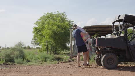 young couple unload trunk on their farmland in australia outback nature