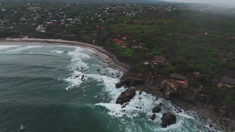 Panoramic-high-angle-aerial-descends-following-rows-of-long-waves-crashing-on-rocks-in-Puerto-Escondido-Oaxaca-Mexico