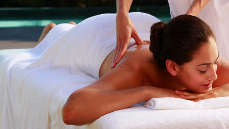 happy brunette enjoying a massage poolside