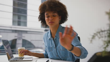 mujer de negocios en una oficina moderna trabajando en una computadora portátil y hablando en el teléfono de escritorio