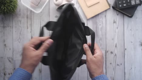 person opening an empty gray backpack