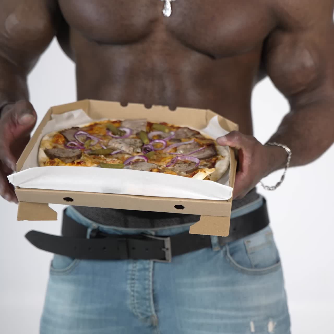 Male torso of african athlete. Young muscular african man with naked torso eating pizza in studio