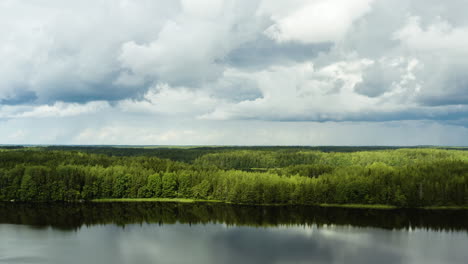 Aerial-view-over-a-reflecting-lakes-and-green-forest,-on-a-calm,-partly-sunny-day,-in-Inkoo,-Uusimaa,-Finland---rising,-drone-shot