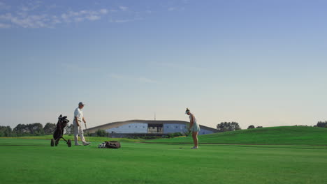 Professional-golf-people-play-game-on-fairway.-Couple-practice-on-sunset-course.