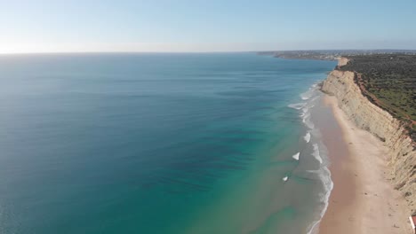 Steep-sandstone-cliffs-on-vast-golden-sand-beach,-Lagos-coastline