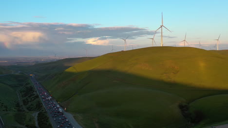 drone shot of a sunlit wind turbines and a highway, sunset in san francisco, usa