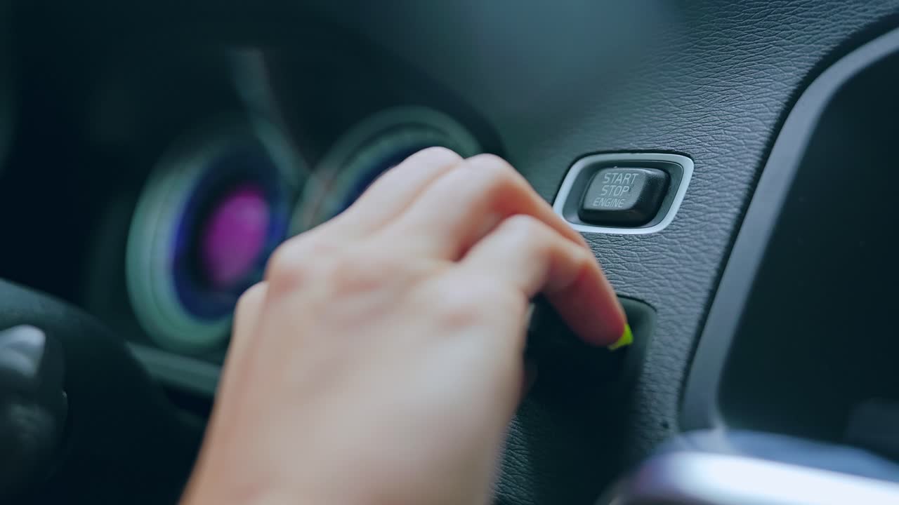 Modern car dashboard and female finger starting engine in elegant slow motion
