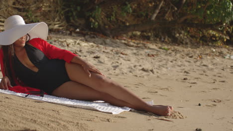 elegante modelo de mujer latina sexy tomando el sol de su lado en la playa tropical, toma de revelación panorámica