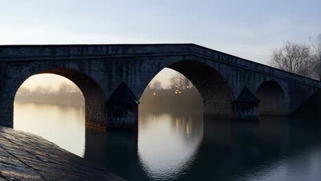 tranquil stone arch bridge over river at dawn or dusk