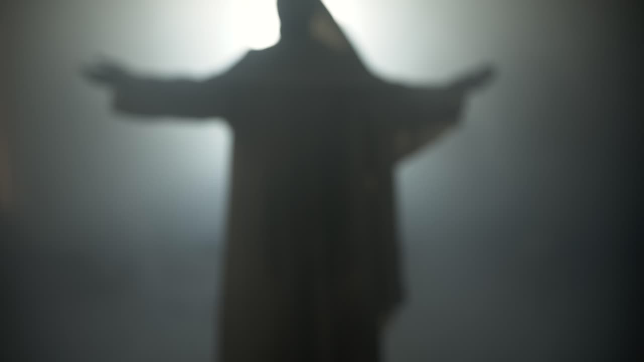 Silhouette of resurrection of Jesus Christ inside the tomb, in bright light, raising his hands in dramatic, cinematic slow motion. Perfect for Easter resurrection visual.
