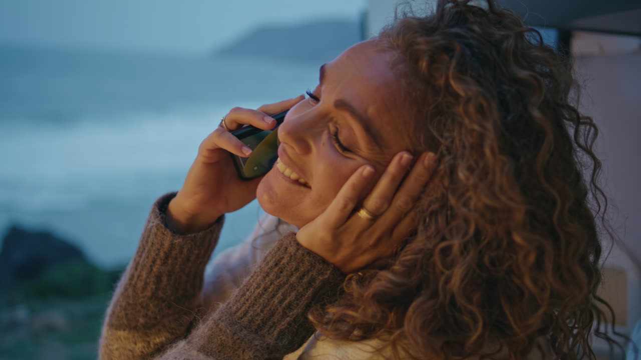 Relaxed traveller speaking cellphone at evening ocean close up. Woman calling