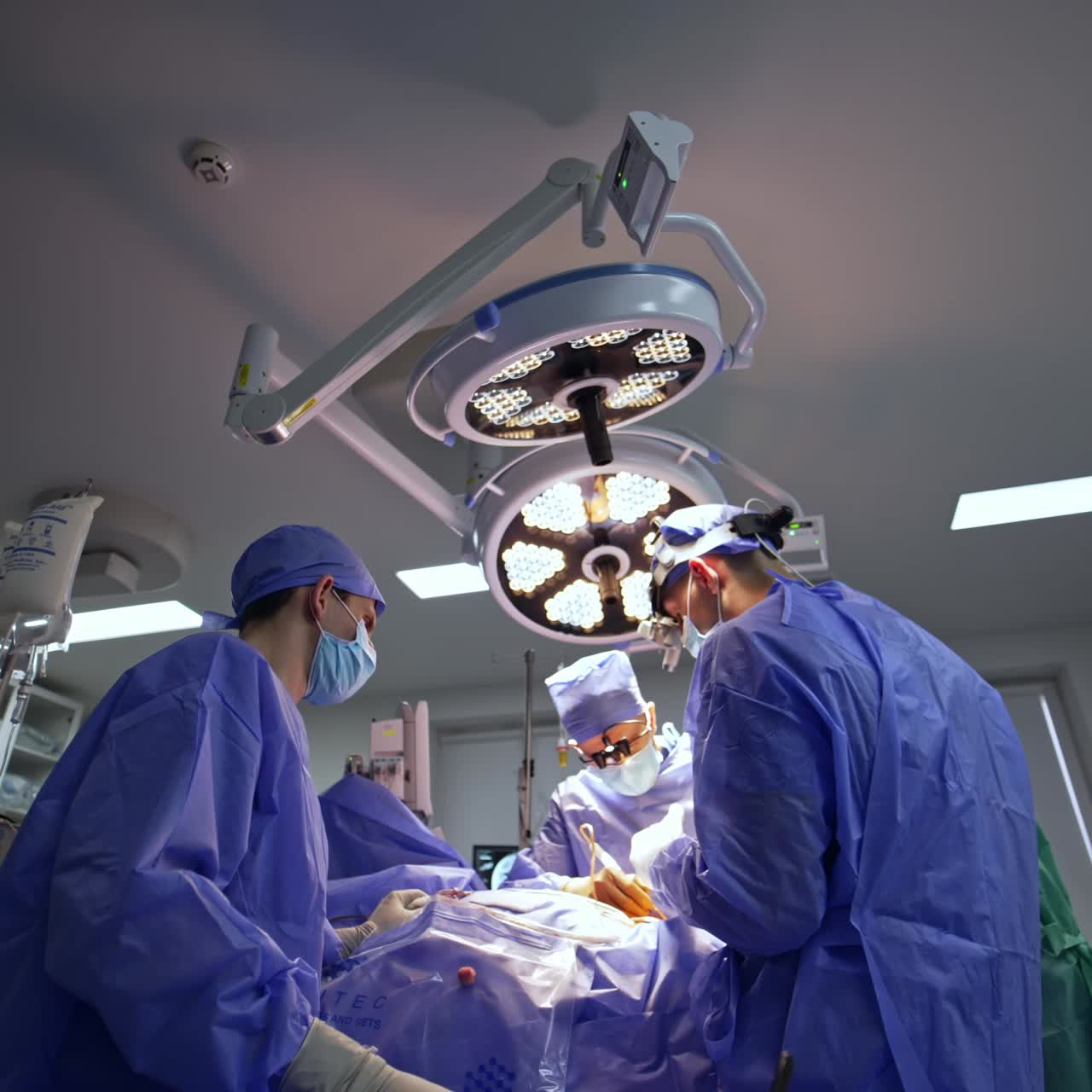 Medical team operating the patient in surgery room. Doctors in device glasses perform neurosurgery. Low angle view