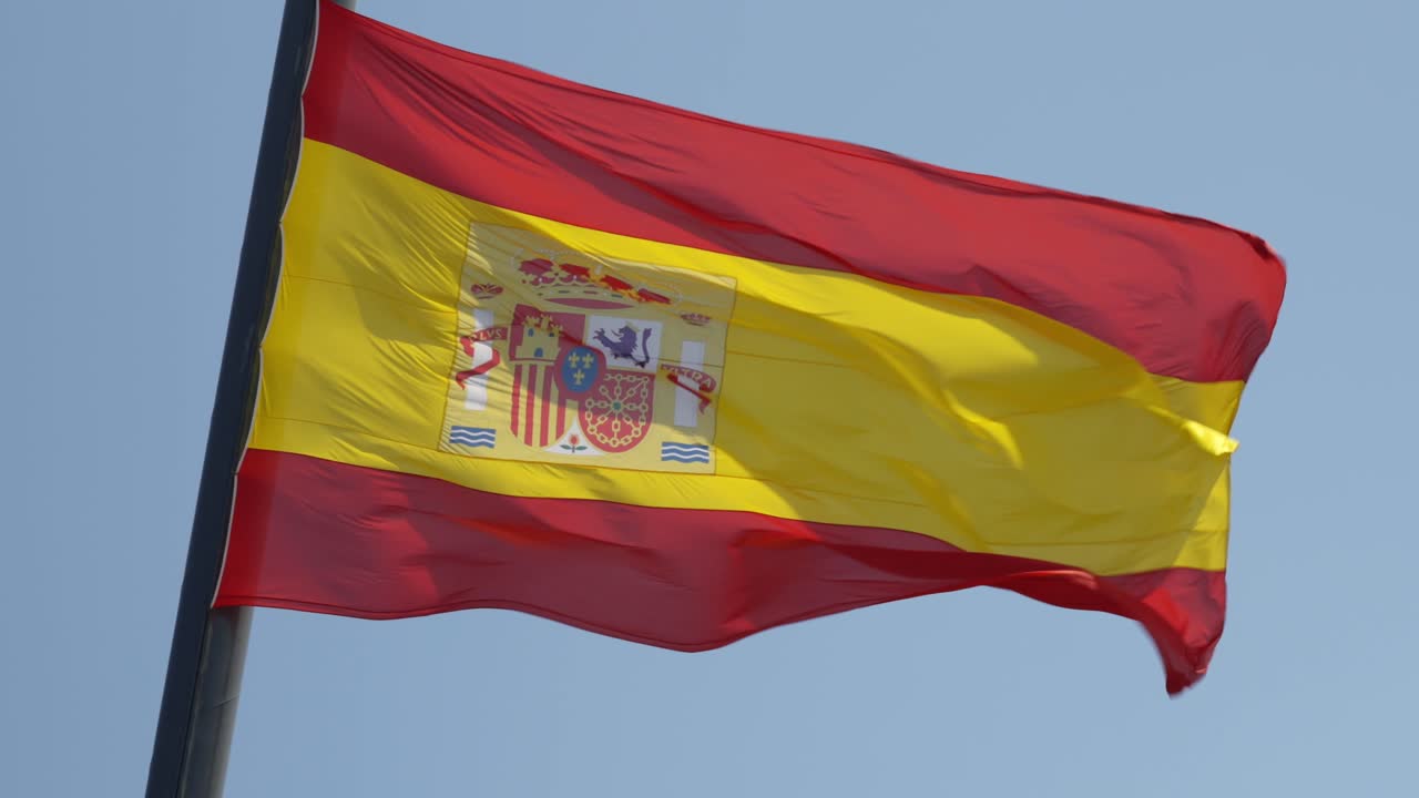 bandera nacional de españa en un viento sobre fondo de cielo azul, verano soleado