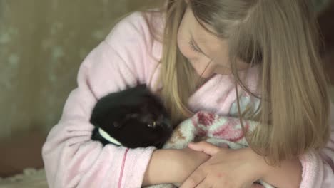 little girl gently hugs her pet cat, holding it in her arms.