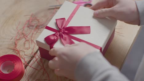 close up shot of man gift wrapping romantic valentines present of perfume in box on table 2