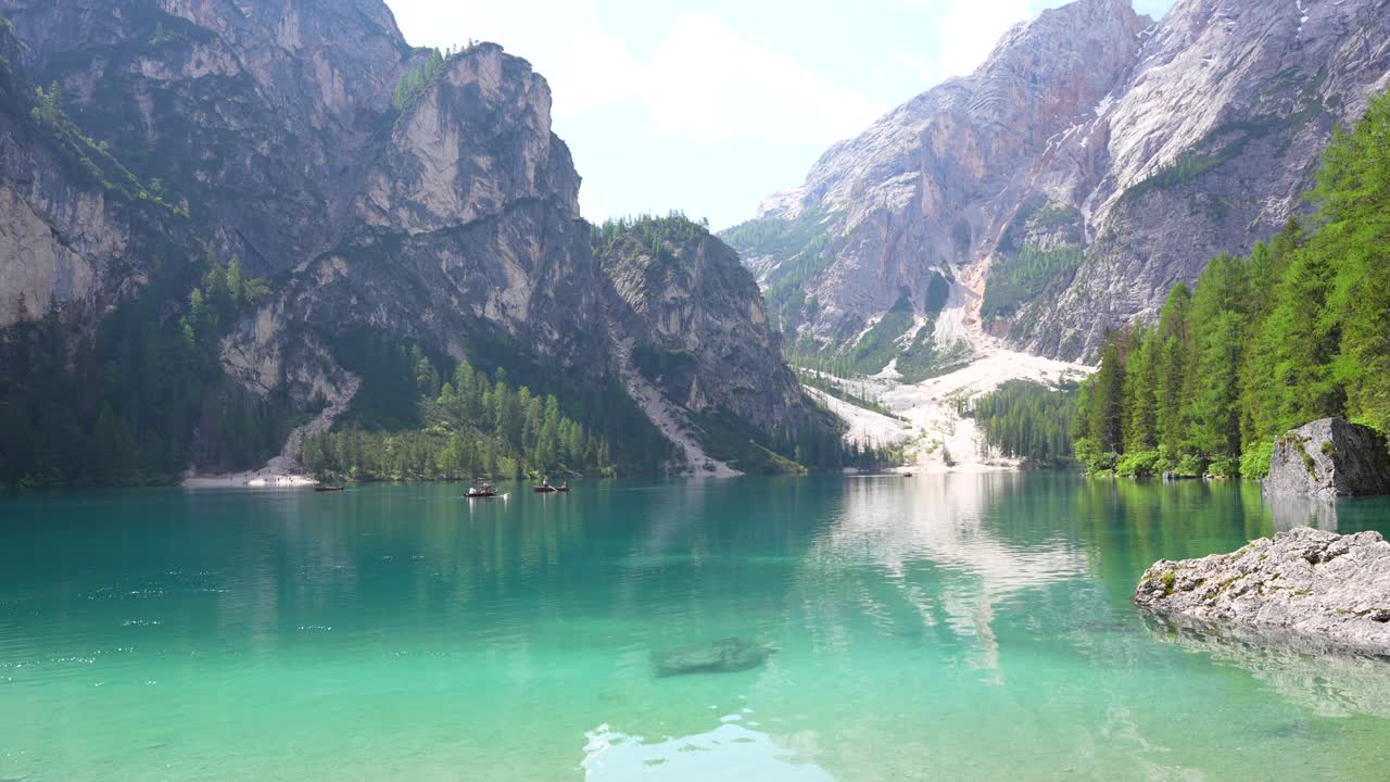 Tranquillo Lago di Braies color turchese e cristallino, con turisti che remano su barche di legno.