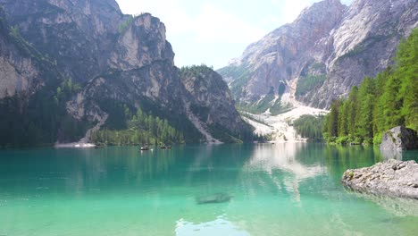 Ruhiger,-Türkisfarbener,-Spiegelartiger-Pragser-Wildsee-Mit-Touristen,-Die-Holzboote-Rudern