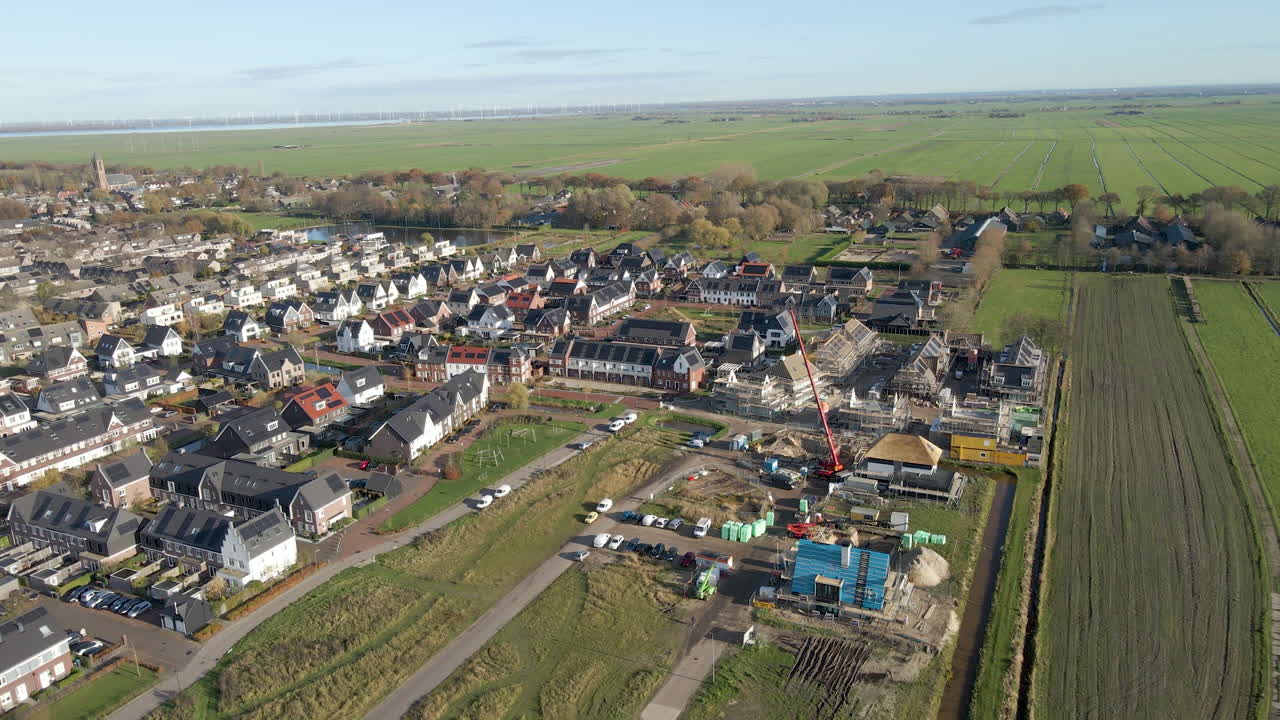 обзор с воздуха строительной площадки на окраине нового пригородного микрорайона, окруженного зелеными лугами в голландской сельской местности
