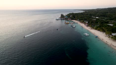 aerial view of the coast, boats, green palms on the sandy beach at sunset