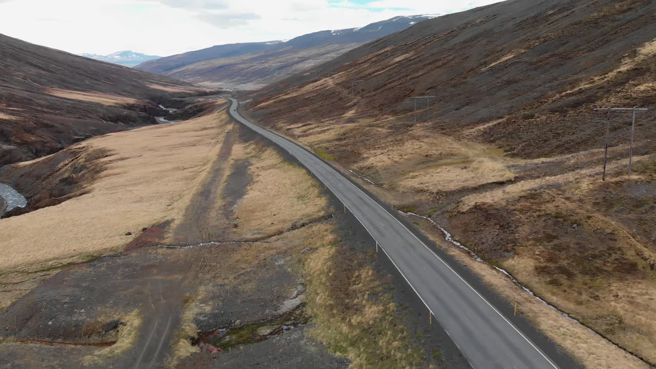 imágenes aéreas de dos autos conduciendo en la carretera islandesa ubicada en las montañas de islandia