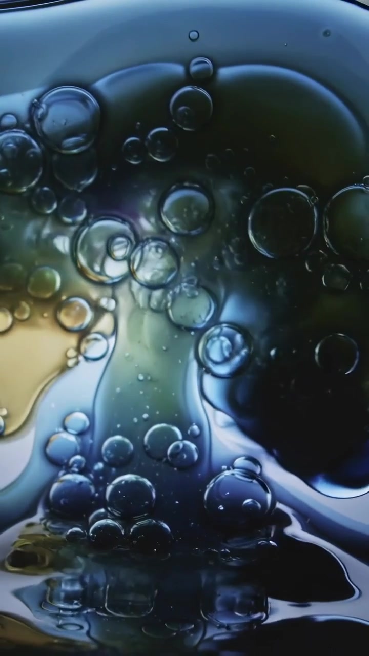 Video verticale: Fluidi che passano dall'ambra al blu con bolle che si evolvono in un bicchiere, in controluce.