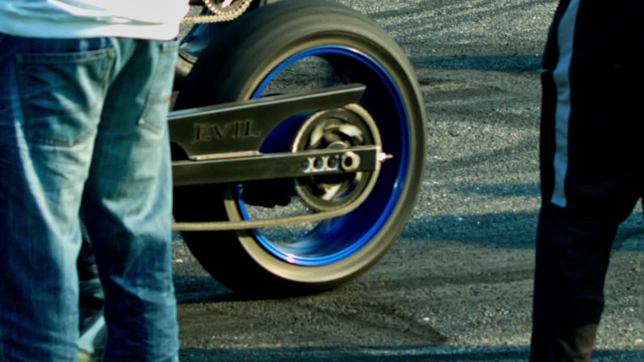 A closeup view of the tires of a racing bike screeching on the roads during street racing. Slow motion.