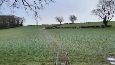 a 4k drone shot flying over a small footbridge in a winter valley