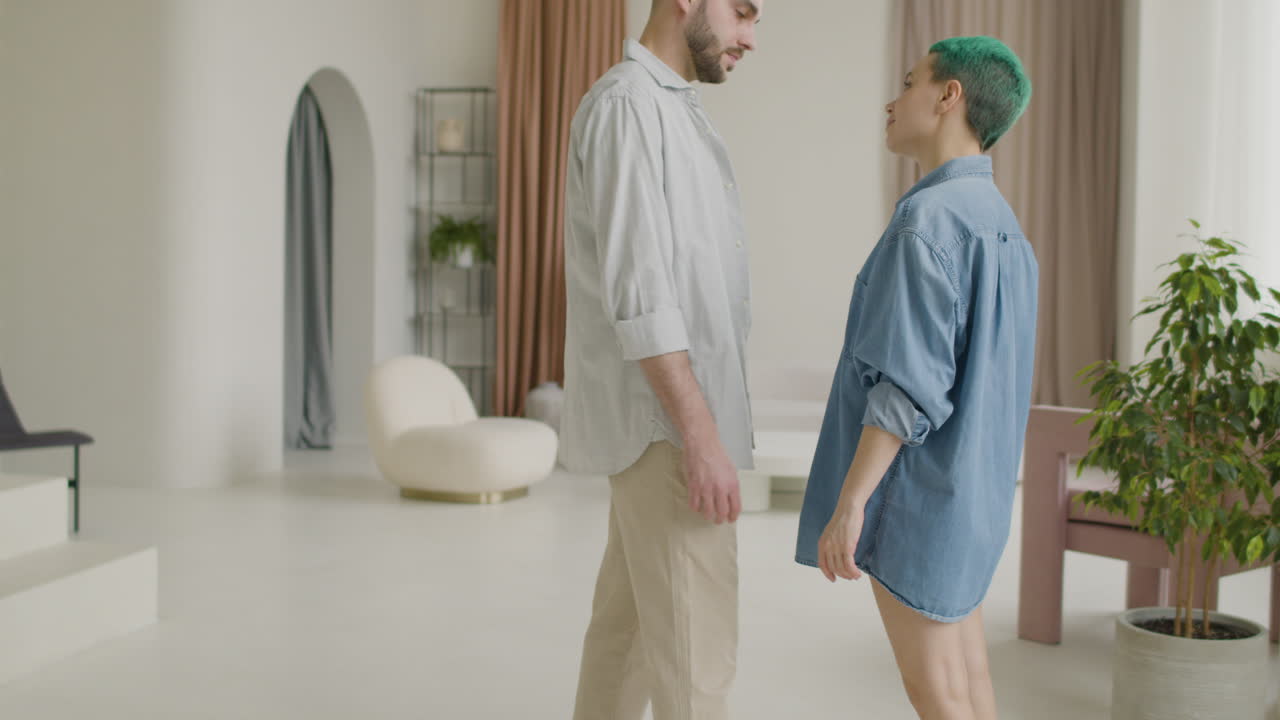 평상복 차림으로 손을 잡고 집에서 서로를 다정하게 바라보는 사랑하는 젊은 부부