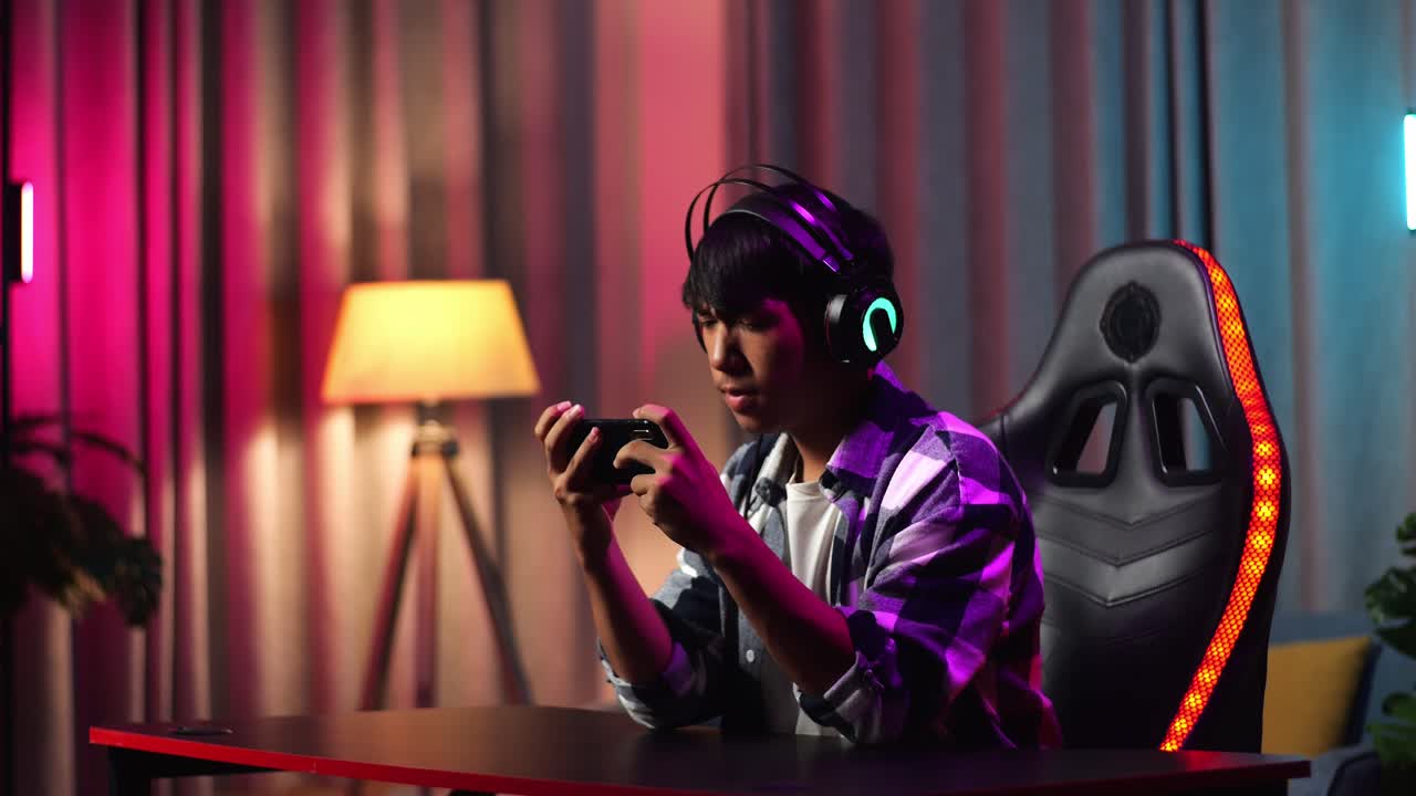 Excited Asian Teen Boy Gamer Playing Video Game On Smartphone
