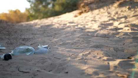 low slide shot of a broken bottle, trash and litter on a natural dirt hiking trail at sunrise