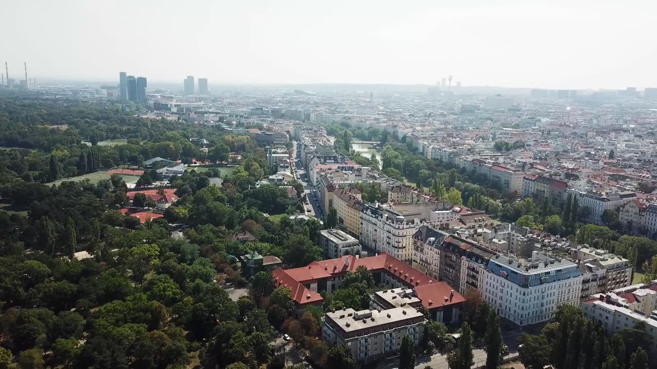 Suburb district with trees and luxury row of houses in Vienna. Cloudy day with downtown and skyscrapers in Background. Capital of Austria. Aerial wide shot.