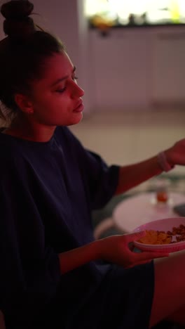 mujer viendo televisión y comiendo bocadillos