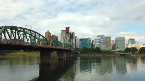 4k short pan left to right of hawthorne bridge frame left crossing willamette river toward downtown portland skyline with mostly cloudy sky