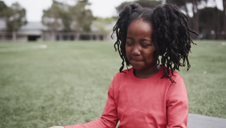 young girl smiling outdoors on school field, enjoying peaceful moment, copy space