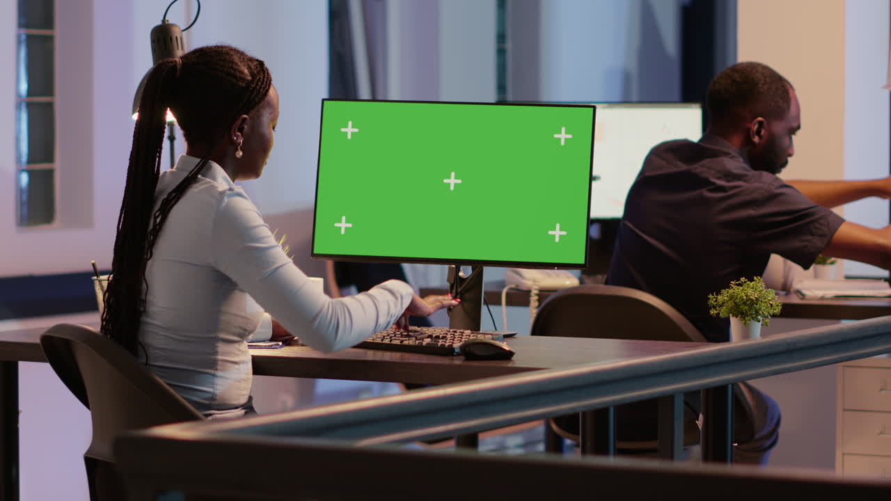 People working in an office with green screen monitors
