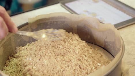 crumble crust is poured into paper lined springform pan for cheesecake