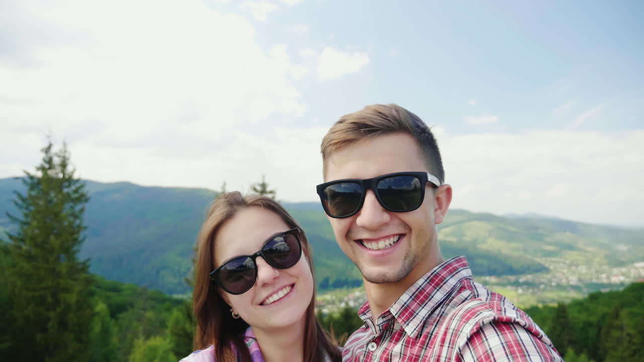 아름다운 산 풍경을 배경으로 사진을 찍는 젊은 활동적인 커플