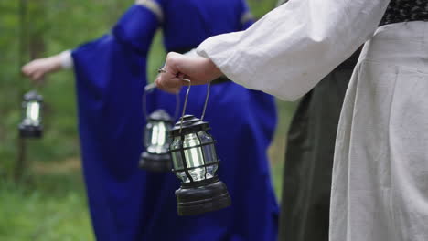 mujeres con vestidos medievales con linternas caminan por la madera