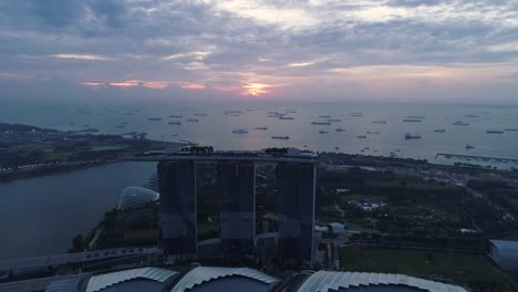marina bay sands hotel at sunrise with distant boats near shore, aerial