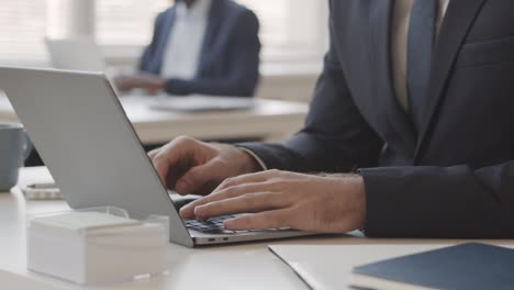 businessman in suit typing on laptop in office